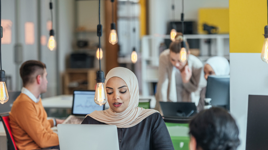 diverse modern office culture woman in headscarf industrial lights hanging over heads